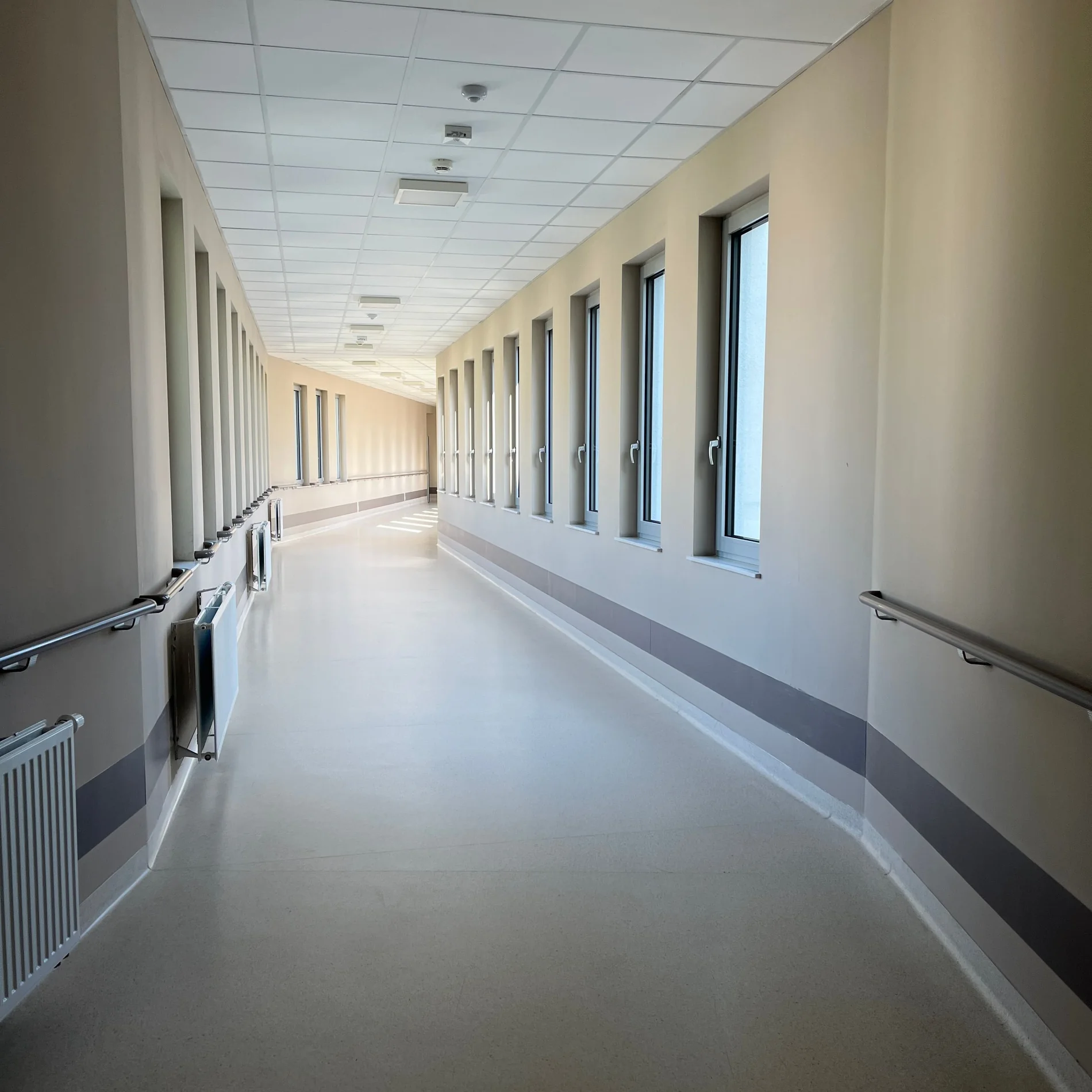 Bright hospital corridor with windows and handrails
