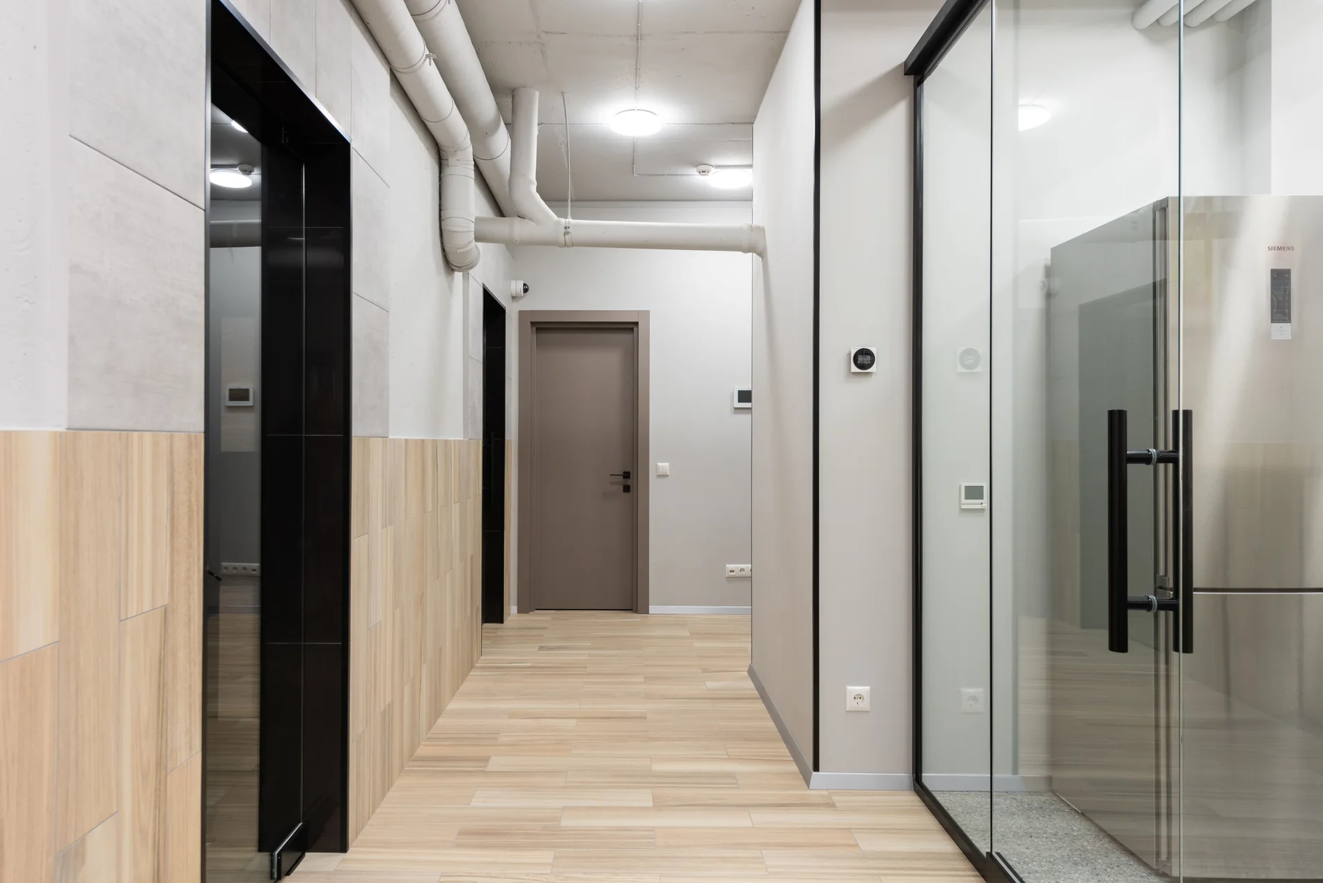 Contemporary office corridor with glass doors and timber flooring
